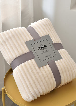 Folded beige blanket with a gray strap and label on a yellow stool.
