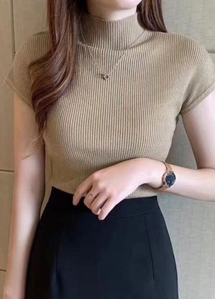 Woman wearing a beige ribbed knit top and black pants against a neutral background