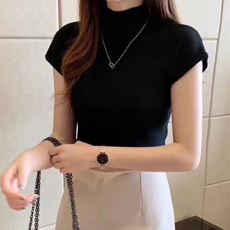 Person wearing a black sleeveless top and a watch, with a neutral background