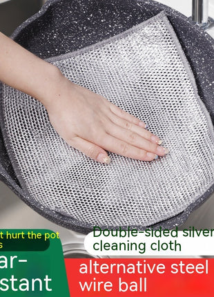 Person cleaning a pot with a double-sided silver wire cleaning cloth.