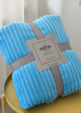 Folded blue blanket with a brand tag on a yellow stand against a white curtain background