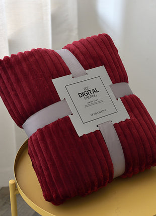 Folded red blanket with a white tag on a yellow surface